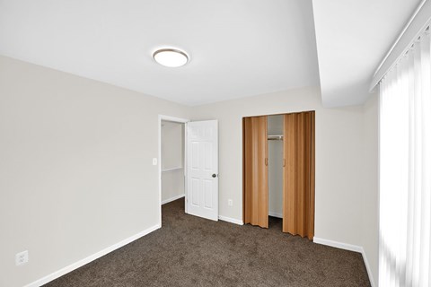a bedroom with a carpeted floor and a door to a closet